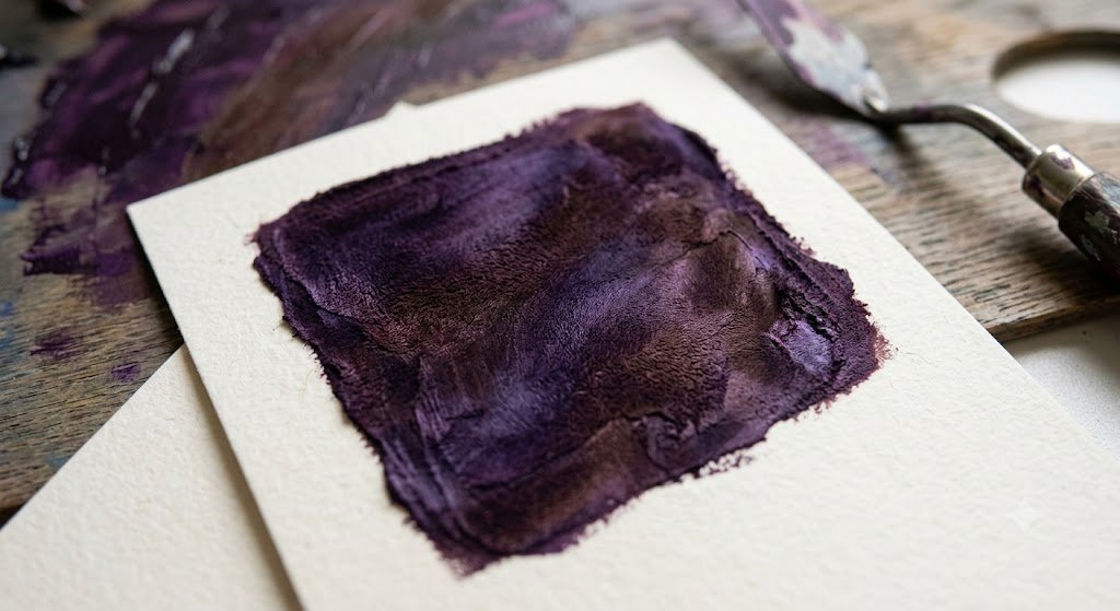 A rich velvet dark purple paint texture swatch showing subtle variations in plum brown and deep violet tones.